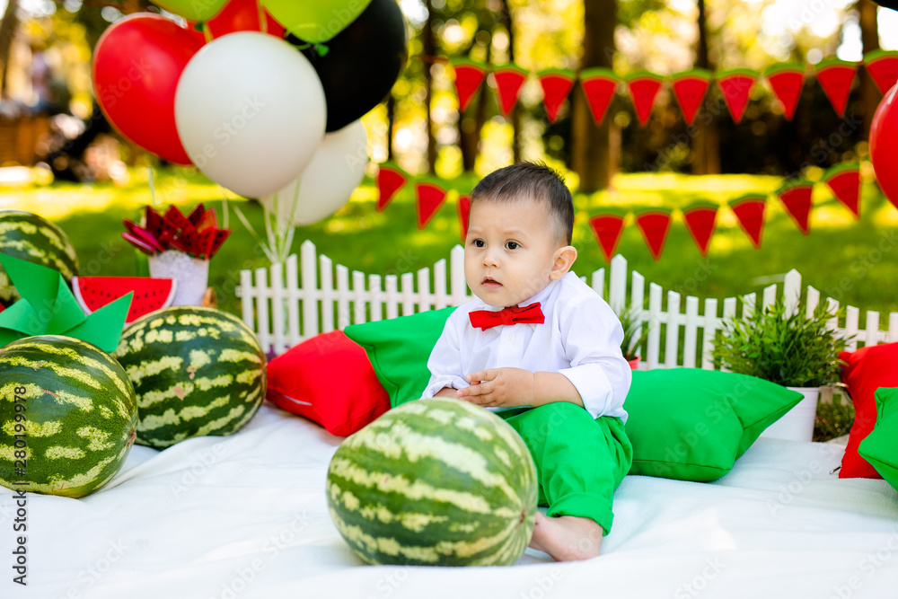 Obraz premium Happy child with big red slice of watermelon sitting on green grass in summer park. Healthy eating concept