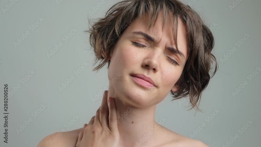 Cute tired young lady with neckache over grey background isolated Cute tired young lady with neckache over grey background isolated
