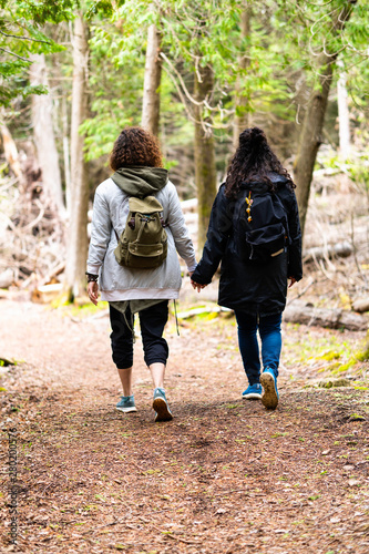 Two curly girls holding hands while having a hike in the forest