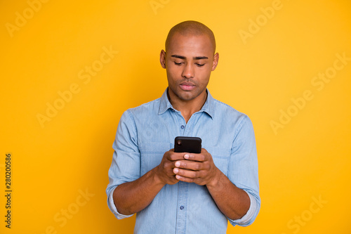 Portrait of focused handsome youth hod hand modern technology search information isolated over yellow background photo