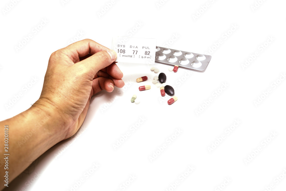 adult male hand holding a white paper data of systolic ,diastolic and pulse after examination with tester tool on white background with bright light and many medicine adult male hand holding a white paper data of systolic ,diastolic and pulse after examination with tester tool on white background with bright light and many medicine