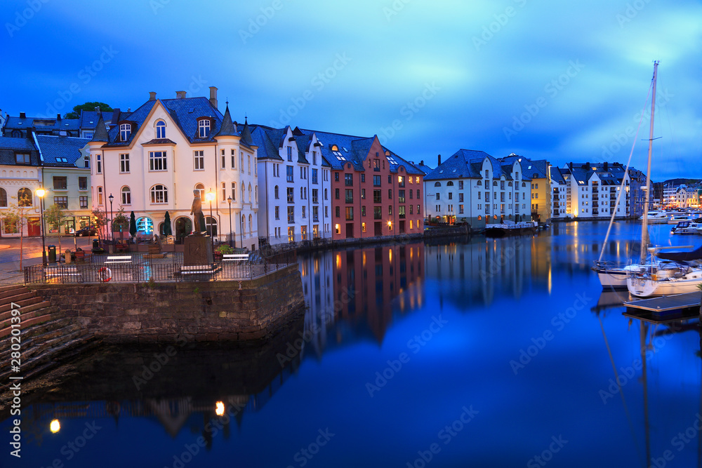 Alesund skyline architecture at dusk, with nice reflections of the houses into the sea in Norway