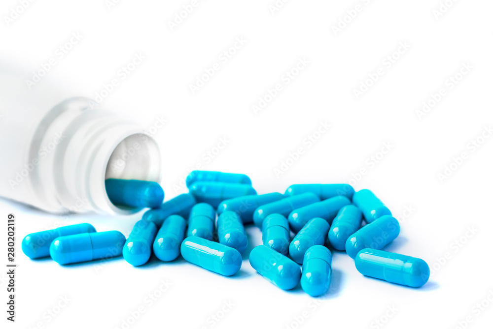Blue capsules, pills isolated on white background with copy space. Capsules in a white jar. Vitamins, nutritional supplements for women's health Blue capsules, pills isolated on white background with copy space. Capsules in a white jar. Vitamins, nutritional supplements for women's health
