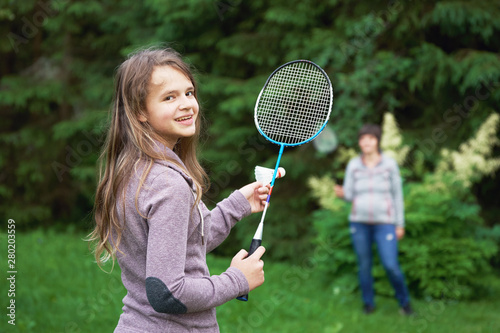 Smiling teenage girl playing badminton with her mother outdoors © Georgy Dzyura