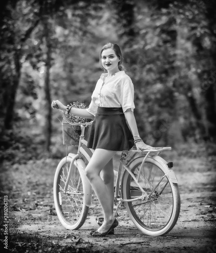Girl in a skirt with a bike in the park