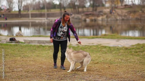 Beautiful girl playing with siberian husky puppy in the park