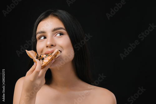 Close up of girl eating italian dish, delicious pizza fast food meal. Very happy girl eats pizza.  Beautiful  young girl with natural make-up and hair style. © Tetiana Moish