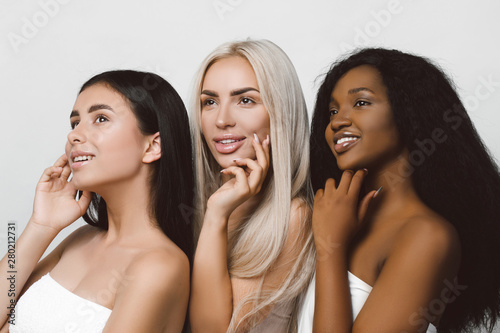 concept of three different ethnicity of women being very close one to each other and posing naked covered with cloth and expressing friendship. Young women with natural make-up and hair style. 