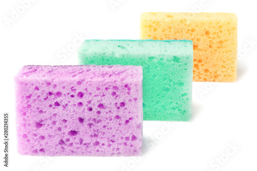 Colored sponges for washing dishes and other domestic needs. Yellow, purple and mint color sponges are located one after the other at a slight angle. Isolate