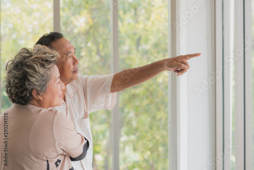Senior Asian couple standing in front of window together with happy smiling on face in special day