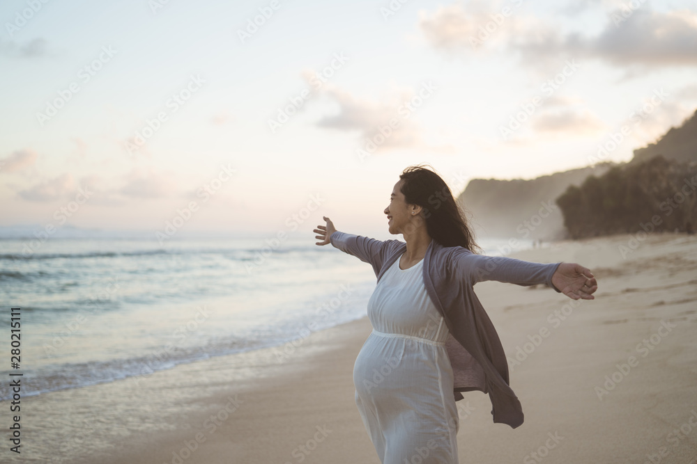 happy pregnant women standing on the beach when they see the ocean - obrazy, fototapety, plakaty 