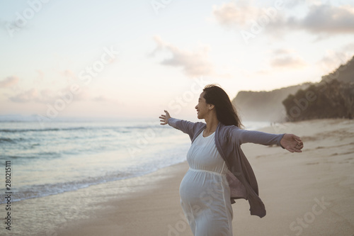 happy pregnant women standing on the beach when they see the ocean