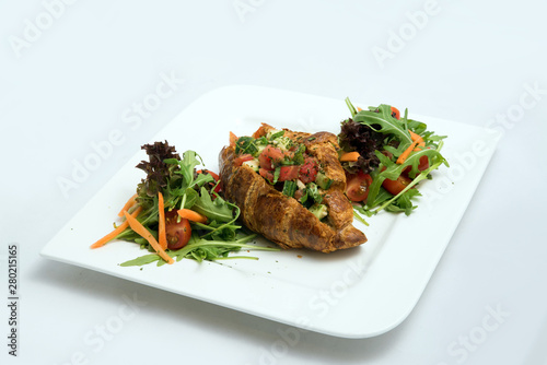 A low contrast Hero shot of a breakfast platter with vegetable-filled croissant with vegetables- carrot, tomato, lettuce on a minimal white background with a 30 degree angle from diagonal perspective.