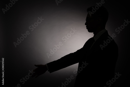 side view of black silhouette of businessman doing greeting gesture with back light