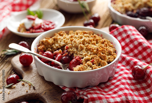 Cherry crumble in a baking dish on a wooden table, close-up