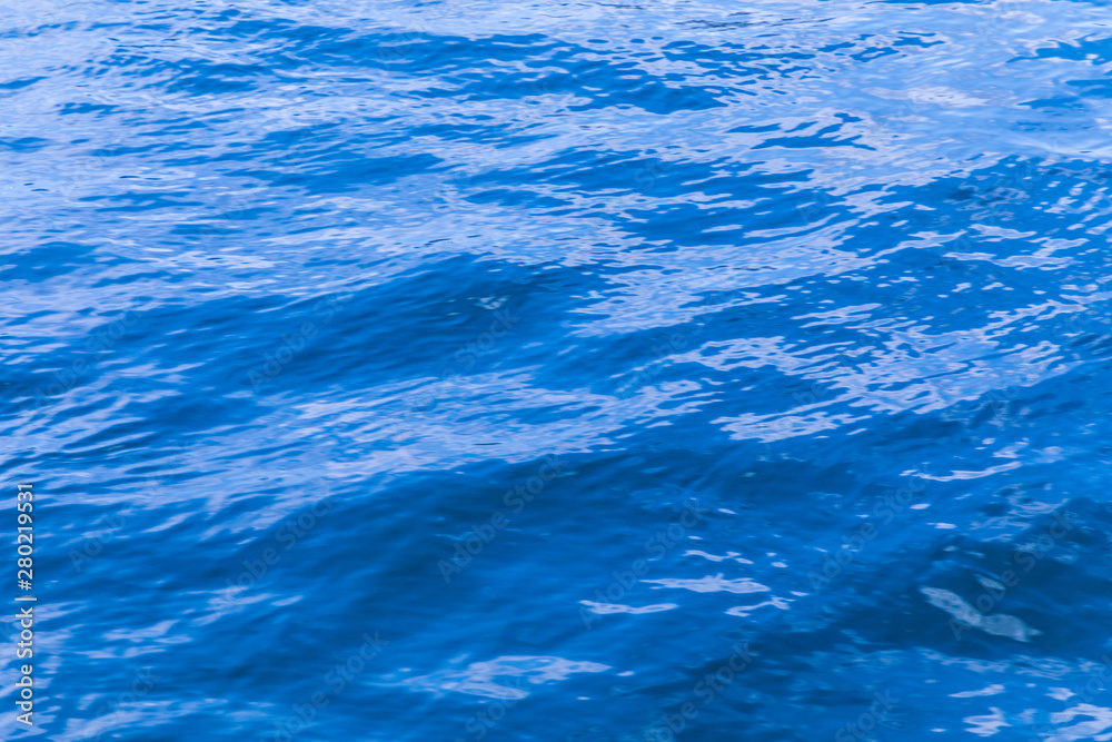 The background or texture of the blue water surface of the river, lake or sea with the waves, ripples and flares The background or texture of the blue water surface of the river, lake or sea with the waves, ripples and flares