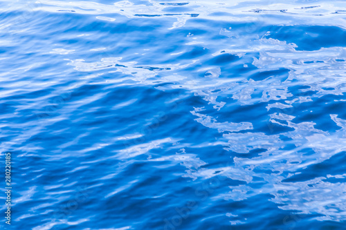 The background or texture of the blue water surface of the river  lake or sea with the waves  ripples and flares