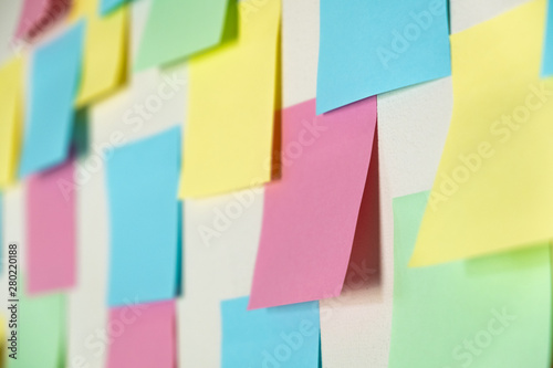 Sticky paper notes on a planning board, close-up view. Planning, brainstorm, diversity or fresh ideas concept - pattern of empty multicolored paper notes