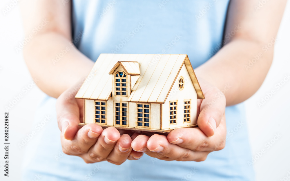 Female hands holding up a small house cabin Female hands holding up a small house cabin