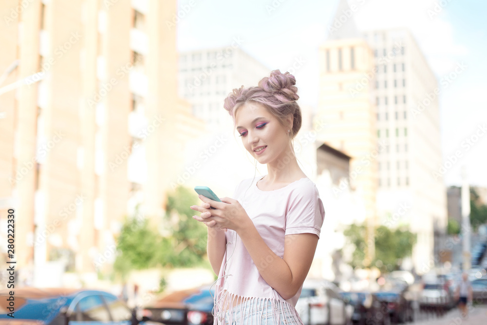 Portrait of a young stylish hipster woman walking down the street dressed in a trendy outfit, a pink hairstyle bun traveling around holding a mobile phone Portrait of a young stylish hipster woman walking down the street dressed in a trendy outfit, a pink hairstyle bun traveling around holding a mobile phone