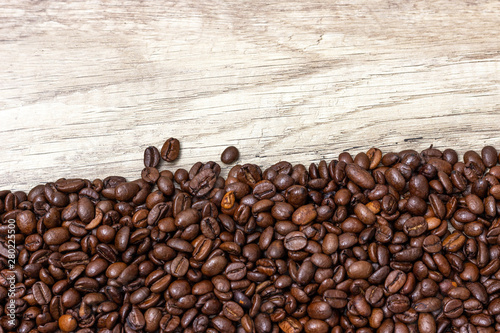 Roasted coffee beans, on a wooden surface.