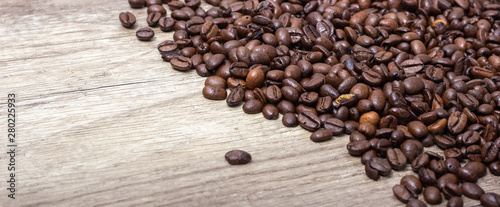 Roasted coffee beans, on a wooden surface.