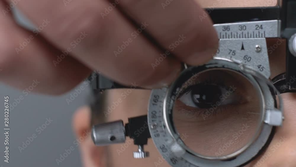 Professional optometrist putting on lens into phoropter to check patient vision Professional optometrist putting on lens into phoropter to check patient vision