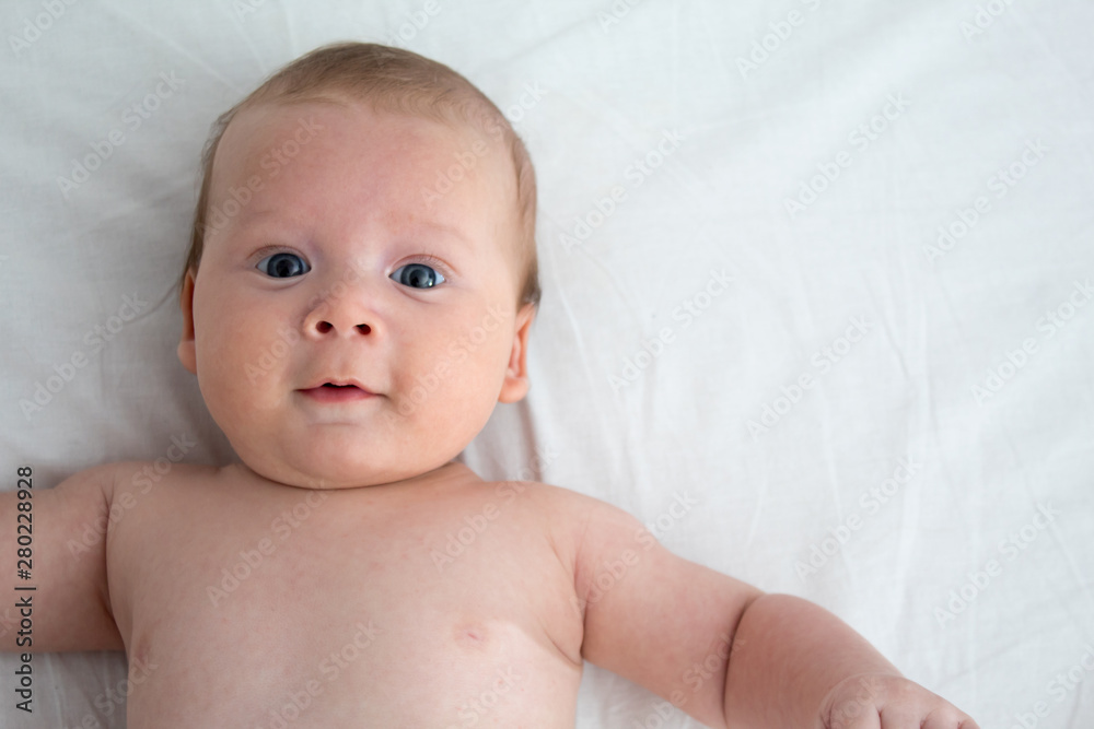 The baby smiles. Newborn lying on a white background .Top view The baby smiles. Newborn lying on a white background .Top view