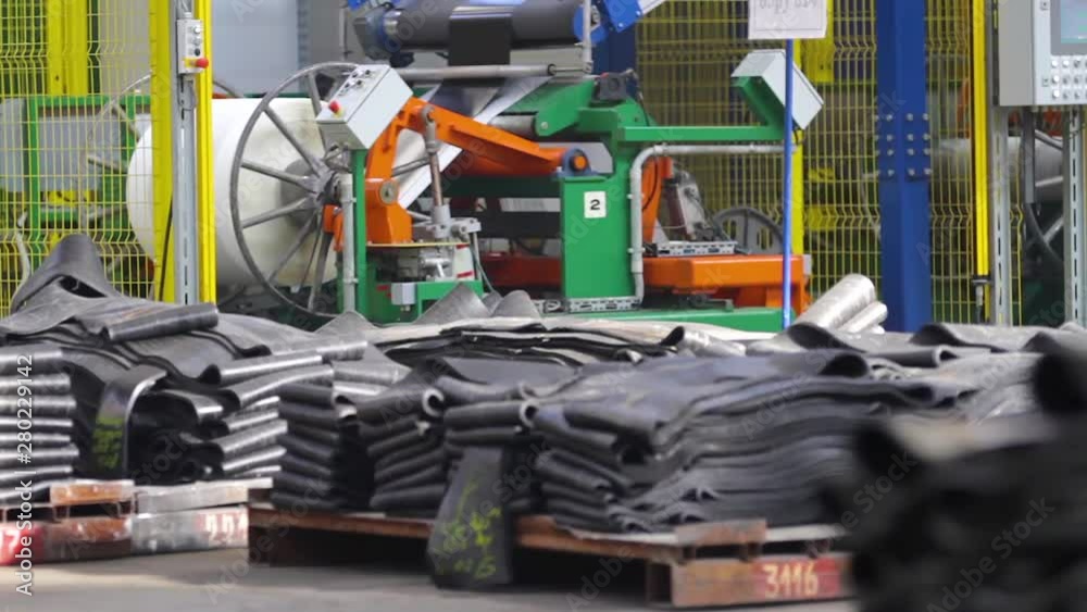 Rubber processing at an industrial plant into rubber products. Rubber tape is fed into machine for further forming and processing at a chemical plant. Industrial space at tire factory. Tire production Rubber processing at an industrial plant into rubber products. Rubber tape is fed into machine for further forming and processing at a chemical plant. Industrial space at tire factory. Tire production