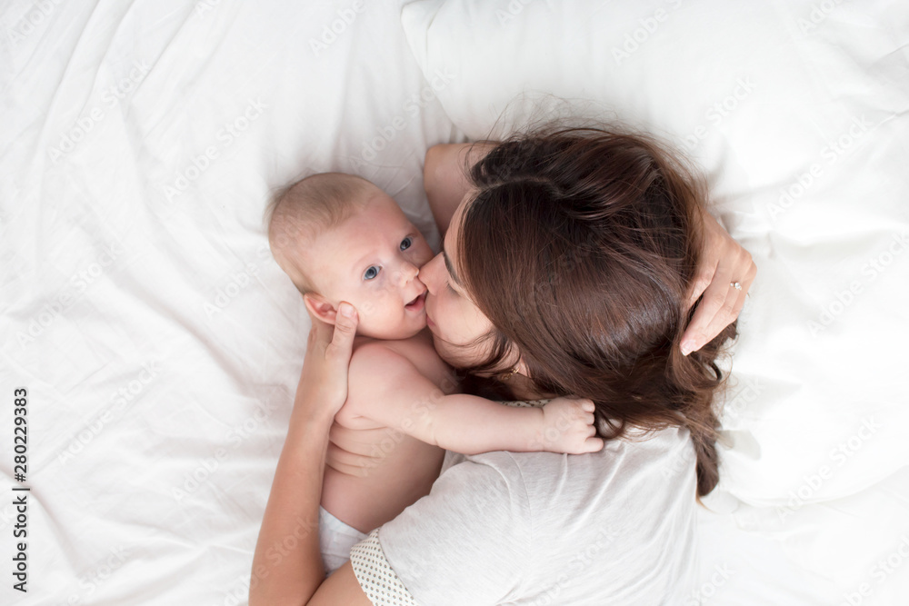 The mother kisses the baby . The brunette lies with a blind child. Top view The mother kisses the baby . The brunette lies with a blind child. Top view