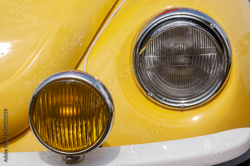 Two Beautiful Round Headlamps Background of a Yellow Retro Car Close-Up.