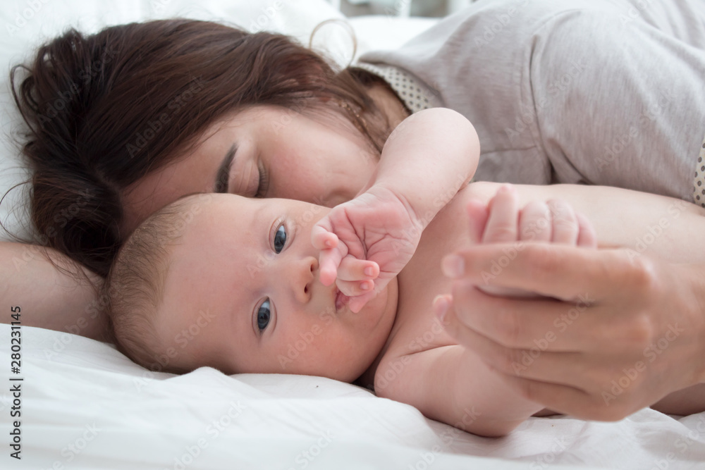 Baby and mom. A brunette woman lies with a blond child. Top view Baby and mom. A brunette woman lies with a blond child. Top view