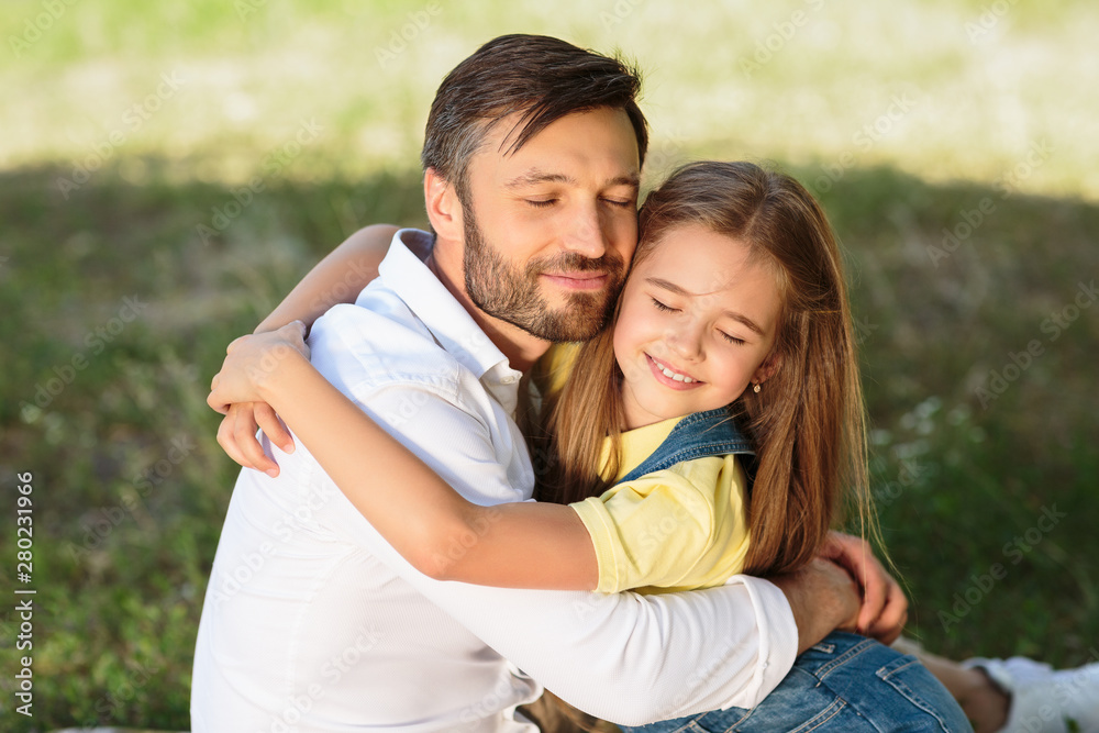 Little girl hugging her father, having picnic outdoors Little girl hugging her father, having picnic outdoors