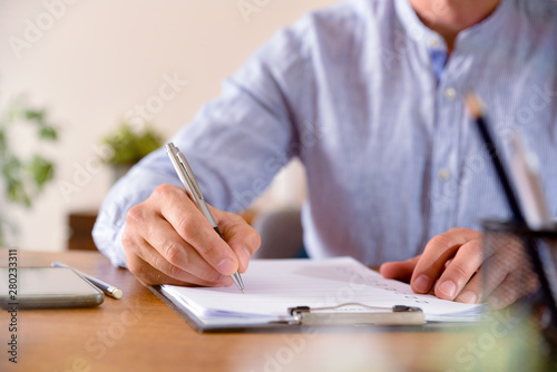 Man filling out a questionnaire on a wooden table front