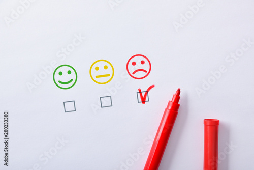 Negative satisfaction with red marker represented with emoticons on paper