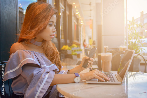 Portrait of successful young woman with laptop in street cafe with sunlight