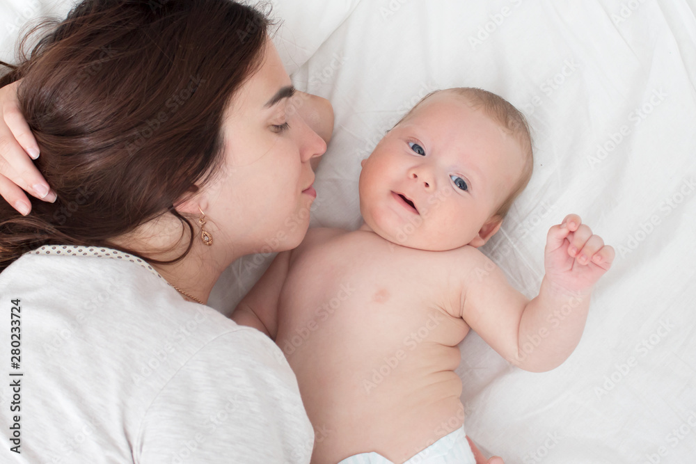 Baby and mom. A brunette woman lies with a blond child. Top view Baby and mom. A brunette woman lies with a blond child. Top view