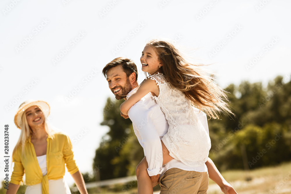 Father piggybacking his daughter, walking and resting outside