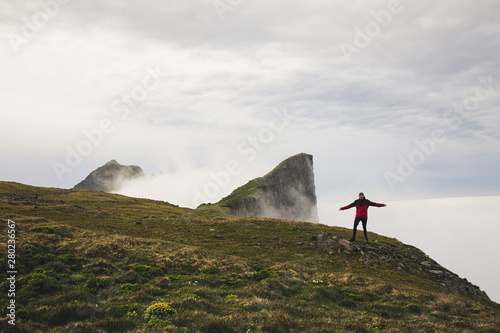 Man standing at the edge of a cliff enjoying a hike at hornstrandir peninsula  westfjord iceland overlooking the northern ocean cover in fog with head in the clouds  photo