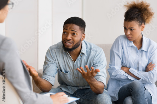 African American Husband Talking To Psychologist Sitting Next To Wife
