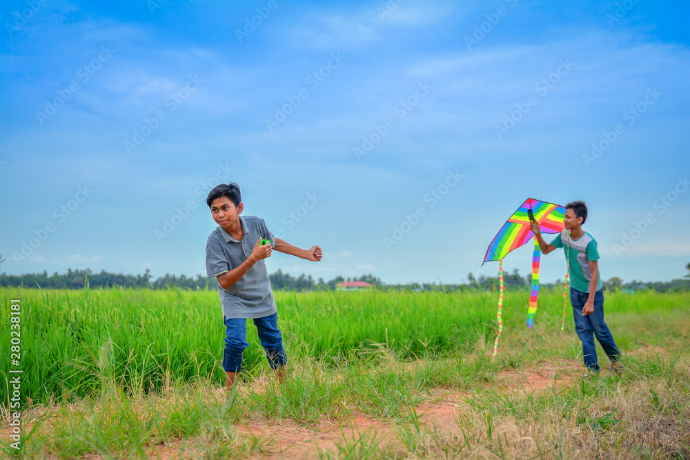 Two friends playing with kite at paddy field in the evening Two friends playing with kite at paddy field in the evening