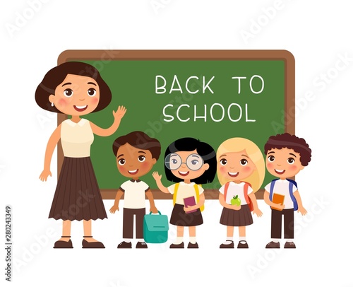 Teacher greeting pupils in classroom flat vector illustration. International boys and girls dressed in school uniform and female teacher pointing at blackboard cartoon characters. 