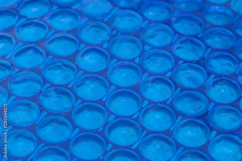 Blue cyan abstract background. Close up of blue bubble plastic used as a swimming pool insulation cover to prevent evaporation of water and to retain the heat Blue cyan abstract background. Close up of blue bubble plastic used as a swimming pool insulation cover to prevent evaporation of water and to retain the heat