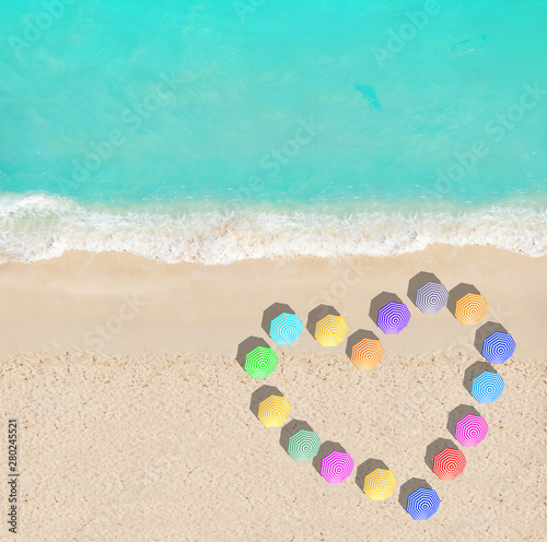 Heart shape of different color umbrellas on beach