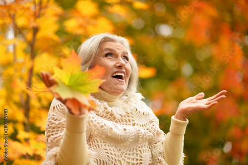 Portrait of happy senior woman smiling and posing in autumn park