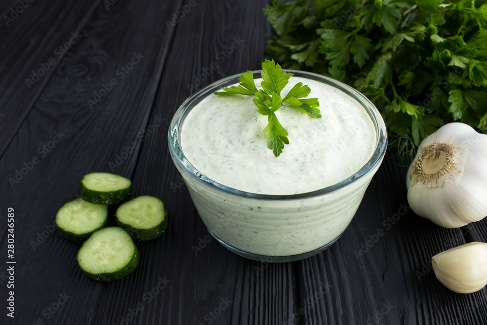 Traditional greek yogurt with cucumber on the black wooden background.Closeup. Traditional greek yogurt with cucumber on the black wooden background.Closeup.
