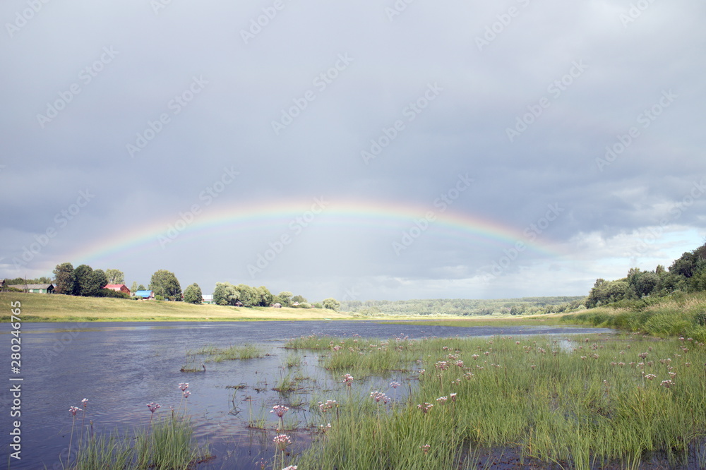 Rainbow after rain over the summer river Rainbow after rain over the summer river