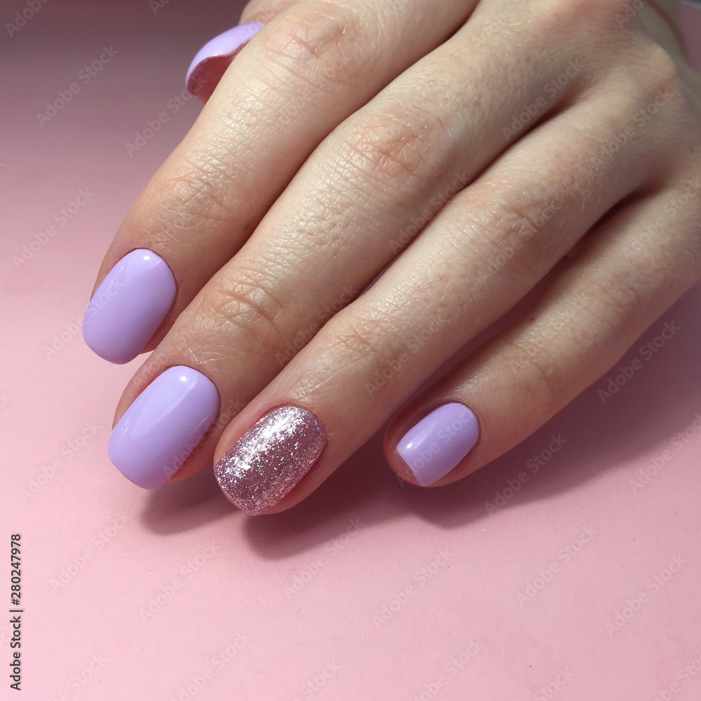 Manicure of different colors on nails. Female manicure on the hand on pink background Manicure of different colors on nails. Female manicure on the hand on pink background