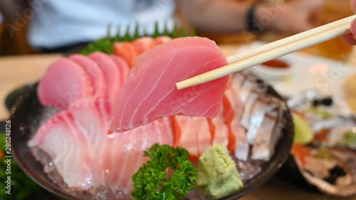 Tuna sashimi slice on chopsticks.