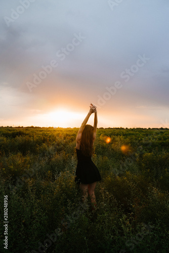 Fototapeta Naklejka Na Ścianę i Meble -  Woman enjoying nature in meadow. Outstretched arms fresh morning air summer Field at sunrise.